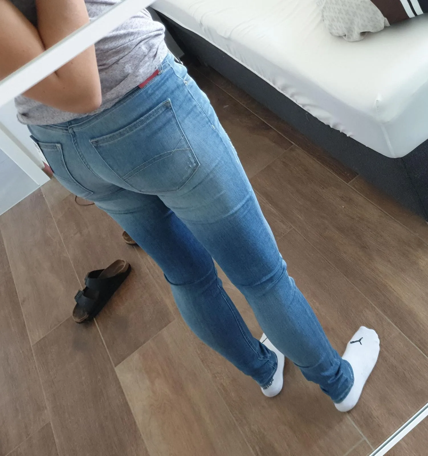 A sexy high quality photo of a girl making a selfie of her ass in tight jeans.