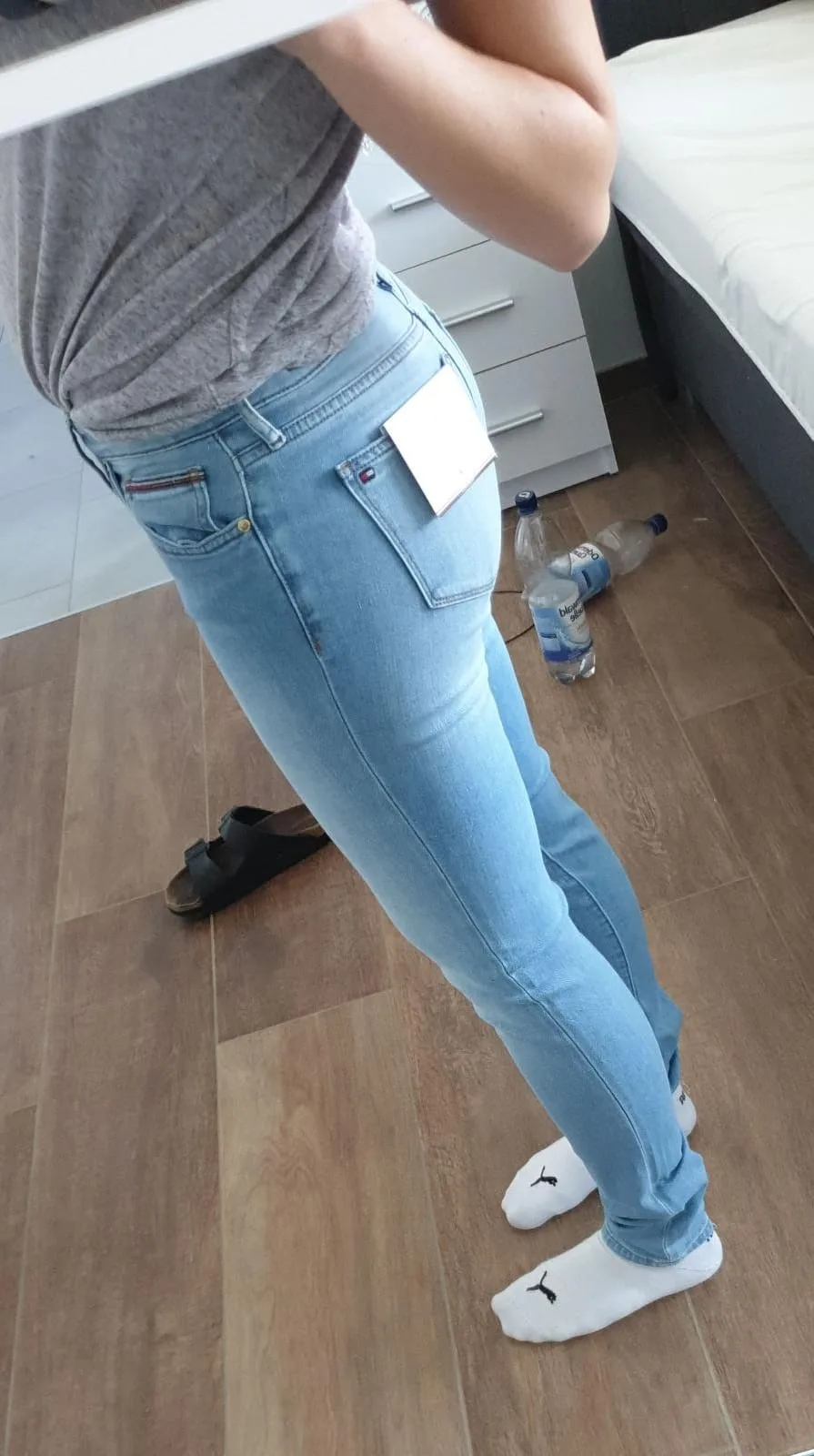 A sexy high quality photo of a girl making a selfie of her ass in tight blue jeans.