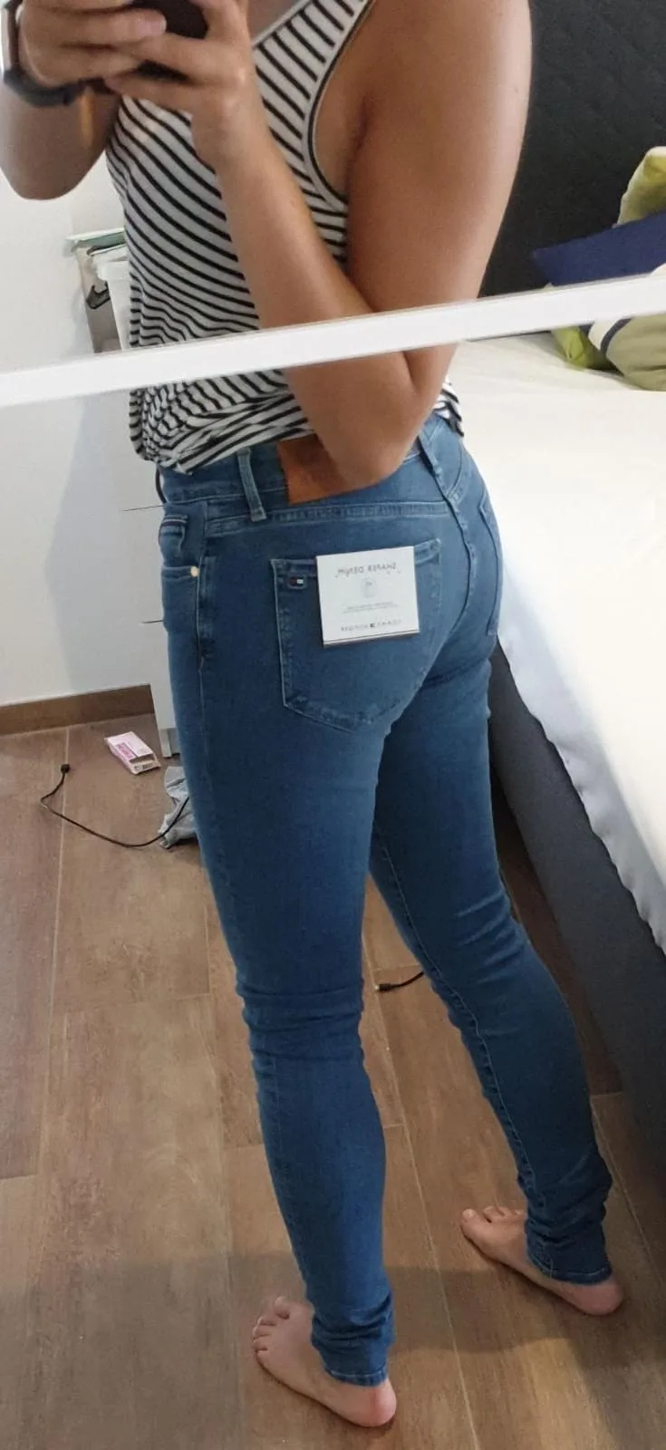 A sexy high quality photo of a girl making a selfie of her ass in tight jeans.