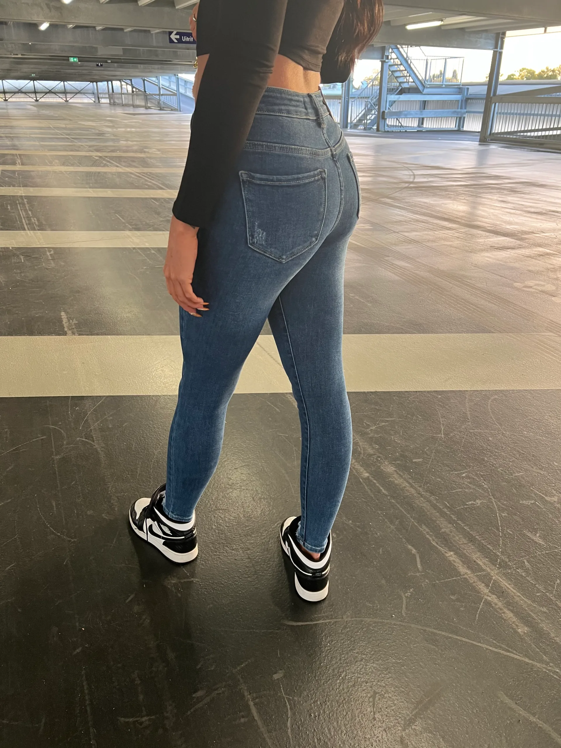 Girl wearing skintight jeans in a garage.
