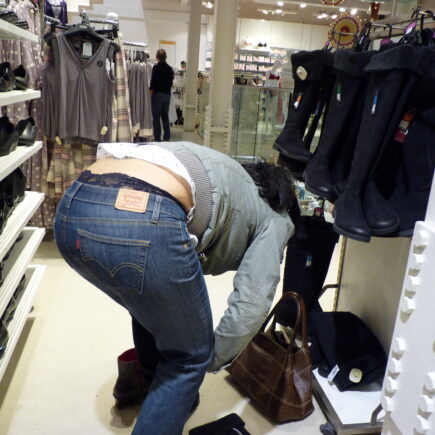 Photo of a girl bending over in tight Levis jeans in a store.